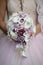 Bride holding wedding bouquet featuring calla lilies with purple accents and accessorized with silver jewelry