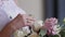 The bride is holding a wedding bouquet in her hands, fingering the flowers