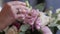 The bride is holding a wedding bouquet in her hands, fingering the flowers