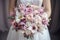 The bride holds a bouquet with lilies and roses