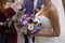The bride holds a bouquet of multi-colored roses, asters, orchids