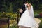 Bride holds groom\'s shoulder walking with him around the park