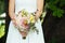 bride holds her bouquet of flowers with ivy roses daisies and hydrangeas in her wedding day