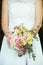 bride holds her bouquet of flowers with ivy roses daisies and hydrangeas in her wedding day