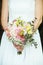 bride holds her bouquet of flowers with ivy roses daisies and hydrangeas in her wedding day