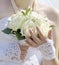 The bride holds white roses in her hand. Beautiful white fragment dress. The wedding design.