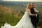 Bride hugs groom from behind while they daydreams on a hill