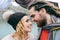 Bride in a knitted hat with pompom and groom with dreadlocks and scarf look at each other with tenderness and love