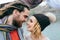 Bride in a knitted hat with pompom and groom with dreadlocks and scarf look at each other with tenderness and love