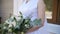 Bride in lace dress holding beautiful white and green wedding flowers bouquet, close-up