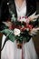 The bride in a leather jacket holds a bouquet