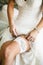 Bride lifting dress showing bridal garter before her wedding ceremony