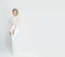 Bride in long white wedding dress on a white background. Luxurious dress in a woman`s body. The girl is preparing to marry