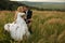 Bride looks happy leaning to a groom on the field