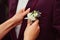 Bride pins white boutonniere to groom& x27;s wine jacket