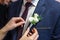 Bride puts groom on boutonniere from pink and whote rose on wedding day