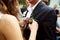 Bride puts a violet boutonniere on groom\'s jacket