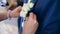 Bride putting on flower boutonniere on groom in black suit