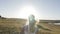 Bride running across the field to meet the sun at sunset