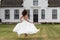 Bride running on a lawn in front of historic house