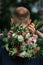 Bride`s arms around grooms neck she is holding colorful wedding bouquet close up