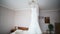 Bride`s dress hanging on a lamp, wedding dress in bride`s room, White wedding dress hanging