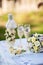 Bride`s and groom`s wedding wineglasses, bottle of champagne and bridal bouquet decorated with white flowers on ceremony table.