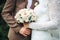 The bride`s hand lies on the bridegroom`s hand with a wedding bouquet of bride`s ring. hands newlyweds