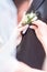 The bride`s hand puts on a boutonniere flower on the groom`s jacket. Bride puts a buttonhole on a grooms suit. close-up