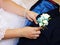 The bride`s hand puts on a boutonniere flower on the groom`s jacket. So close.