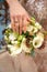 Bride`s hand on the wedding bouquet. women`s beautiful hand with an engagement ring.