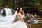 Bride`s walk in a white dress near a mountain waterfall outside