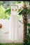 The bride`s wedding dress with a lace transparent corset and a beige bodice on a hanger near a white stone fence and a