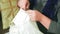 The bride sews her wedding dress by hand with a needle and thread