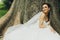 Bride sits behind an old huge tree