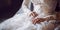 The bride sits in a white lace wedding dress with long sleeves. Women\\\'s hands