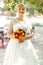 Bride smiles standing with a bouqet on a street in shiny morning