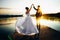 Bride is spinning in a white dress holding hand the groom on the bank of the lake at sunset