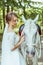 Bride stands near white horse