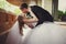 Bride touches groom\'s head tenderly while he bends her over stan