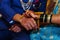 bride tying raw turmeric band to groom`s hand during hindu wedding rituals.