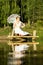 Bride with umbrella sitting on bridge