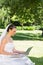 Bride using laptop on grass at garden