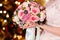 The bride in a veil holds a beautiful bouquet of delicate roses. The lights in the background. French manicure on nails. women`s