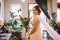 Bride waiting for the big moment. Young bride in beautiful dress holding bouquet of flowers posing near window at home. Wedding