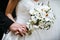 Bride with wedding bouquet of white orchids and groom holding ea