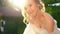 Bride in wedding dress with bare shoulders standing in rays of setting sun