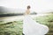 Bride in wedding dress posing on grass with beautiful landscape background