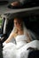 Bride in wedding dress sits in limousine