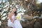 Bride in the wedding dress sits on the roots of a tree in the middle of the stones on the background of tropical trees